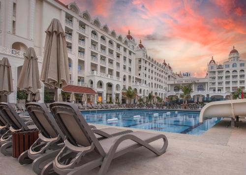 un hotel con sedie e una piscina di fronte a un edificio di Oz Hotels Side Premium a Side