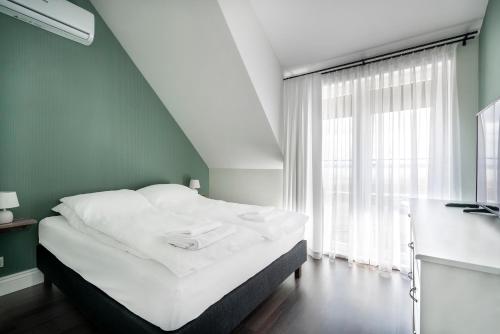 uma cama branca num quarto com uma janela em W Starym Porcie em Krynica Morska