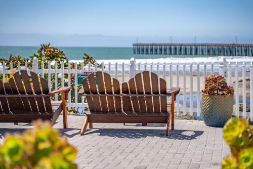 two chairs sitting next to a white fence at the beach at Shoreline Inn...on the beach in Cayucos