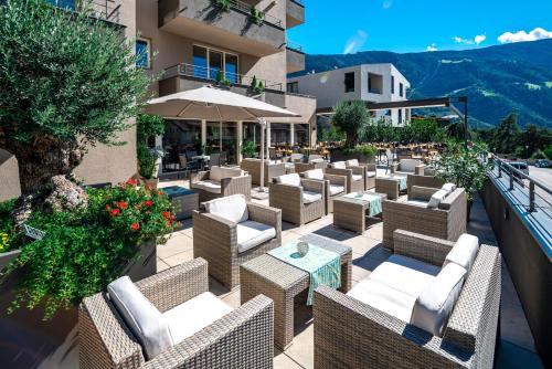 a patio with chairs and tables on a building at Vitalpina Hotel Waldhof in Rablà