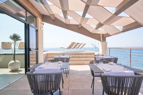 a restaurant with tables and chairs with the ocean in the background at Palace Lido Hotel & Suites in Marina di Cecina