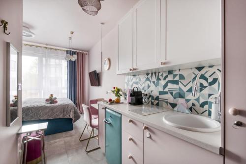 een keuken met een wastafel en een bed in een kamer bij Apartamenty MetroPark Krzemieniecka-Lux in Warschau