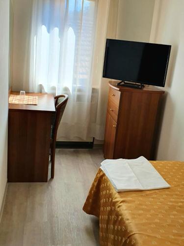 a room with a tv and a desk with a bed at HOTEL PERLA in Massa Lombarda