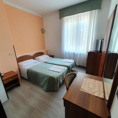 a hotel room with two beds and a table at HOTEL PERLA in Massa Lombarda