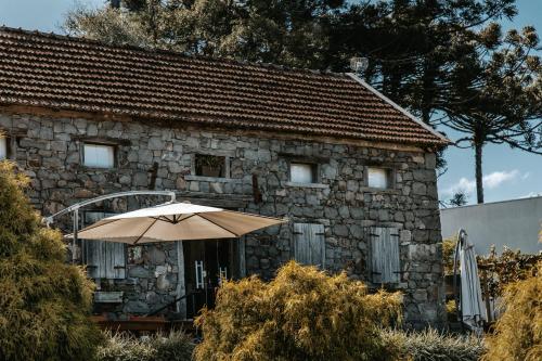 uma casa de pedra com um guarda-chuva em frente em Pousada Cantelli em Bento Gonçalves