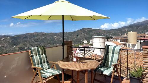 a table and chairs on a balcony with an umbrella at Casa TRIGO in Cómpeta