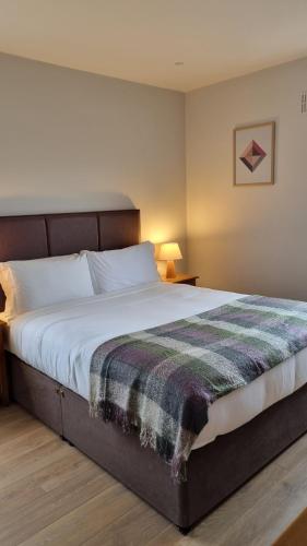 Un dormitorio con una cama grande con una manta. en Inch Beach Cottages, en Inch