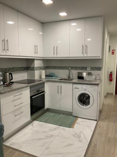 cocina con armarios blancos y lavadora en magnifico apartamento, en Albufeira