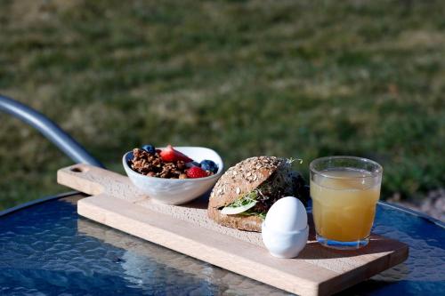 a sandwich and eggs and a bowl of fruit and a drink at Enkegården Gårdshotell in Ängelholm