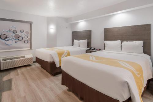 a hotel room with two beds with white sheets at Quality Inn & Suites Richardson-Dallas in Richardson