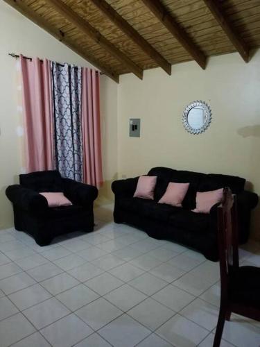 a living room with two black couches and pink pillows at Oak Villa Montego Bay in Montego Bay