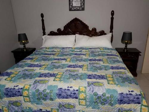 a bed with a colorful quilt on top of it at Oak Villa Montego Bay in Montego Bay