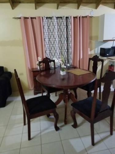 a dining room table and chairs with pink curtains at Oak Villa Montego Bay in Montego Bay