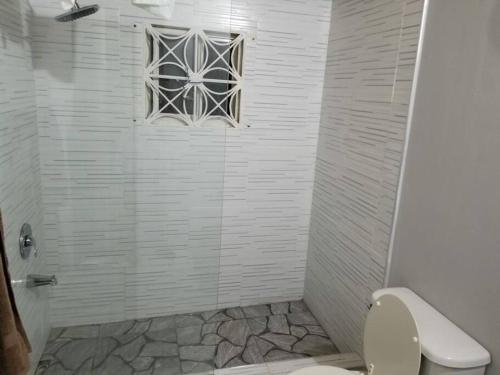 a bathroom with a shower with a window and a toilet at Oak Villa Montego Bay in Montego Bay