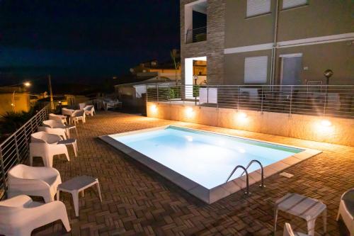 a swimming pool with chairs and a building at night at Rooms Dream Tropea in Tropea