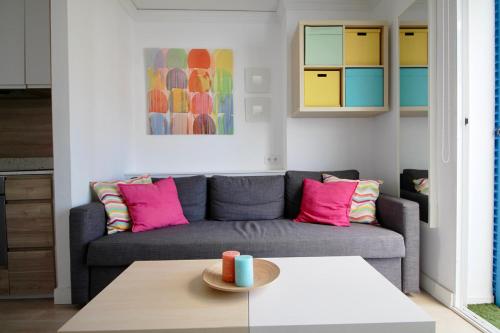 un soggiorno con divano grigio e cuscini rosa di La Alberca 16 a Denia