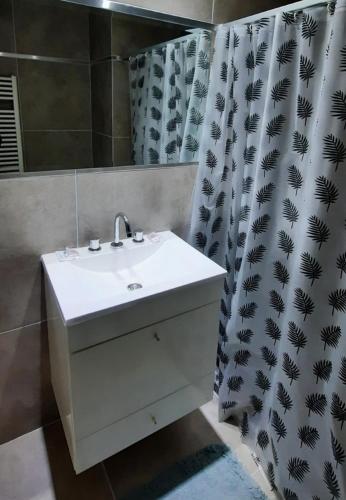 a bathroom with a white sink and a shower curtain at Departamento Calchines con cochera in Santa Fe