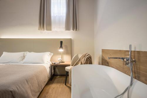 a bedroom with two beds and a bathtub next to a desk at Botrona B&B in Scarlino