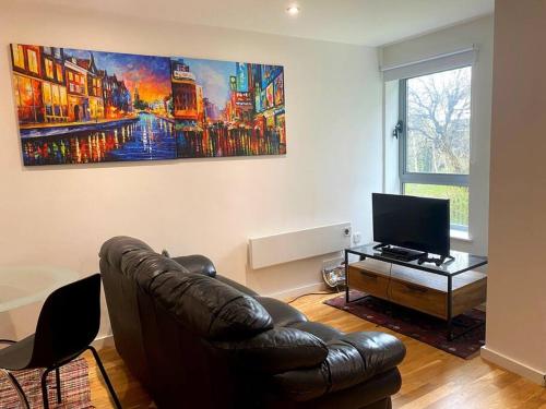 ein Wohnzimmer mit einem Ledersofa und einem TV in der Unterkunft Entire Studio in picturesque City Islands - Short Walk from Leeds Centre in Leeds