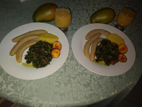 two plates of food on a table with glasses of orange juice at Blue Royalty in Portmore