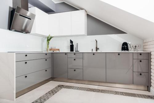 a kitchen with white cabinets and a staircase at Orbis in Pisz