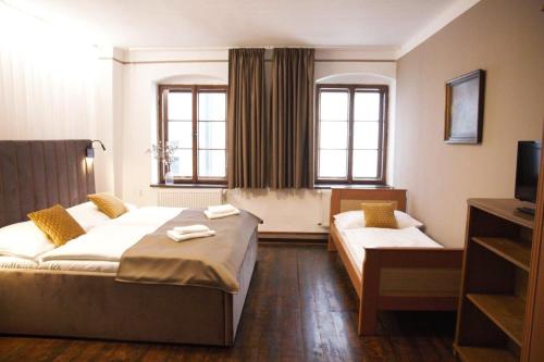 a hotel room with two beds and a tv at Hotel Svambersky dum in Český Krumlov