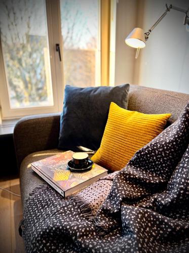 a book sitting on a couch with a cup on it at L'atique by Agelandkaai be with Parking in Ghent