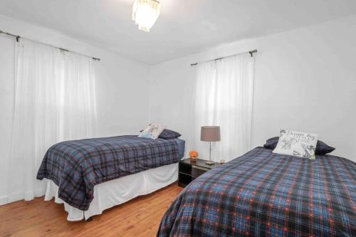 2 camas en un dormitorio con paredes blancas y cortinas blancas en Cozy house to call home away from home, en Maryland Heights