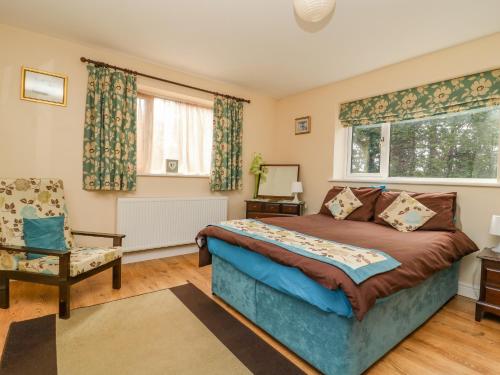 a bedroom with a bed and a chair and a window at 1 Pines Farm Cottages in Ulleskelf
