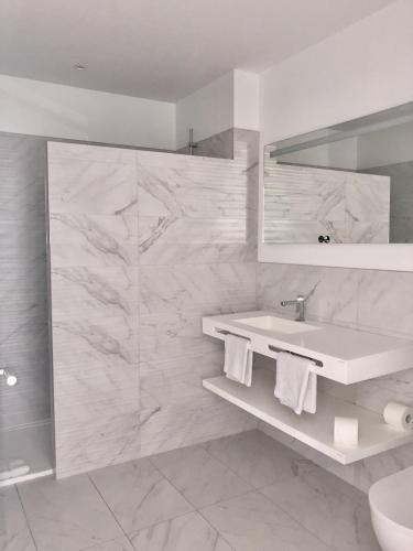 a white bathroom with a sink and a mirror at HÔTELYA - Lille Villeneuve d'Ascq in Villeneuve d'Ascq