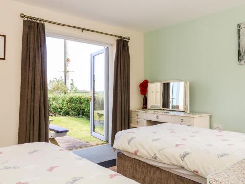 una camera da letto con due letti e una porta scorrevole in vetro di 2 Pines Farm Cottages a Ulleskelf