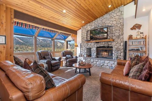 a living room with leather furniture and a stone fireplace at 053 - Glass House on the Ridge in Big Bear Lake