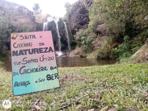 a sign in front of a waterfall at Cachoeira do Alemão - Recanto dos Arcos in Balsa Nova