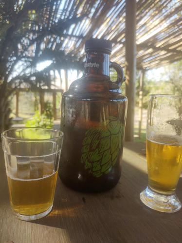 a bottle of honey and two glasses on a table at Cachoeira do Alemão - Recanto dos Arcos in Balsa Nova