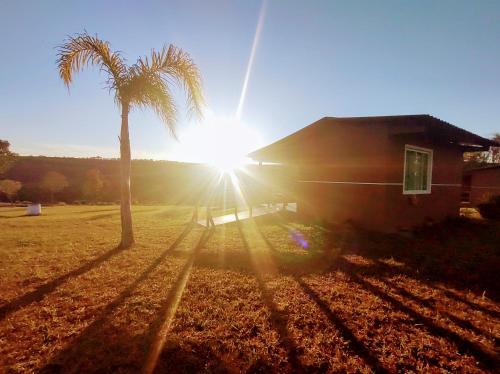 a palm tree next to a house with the sun at Cachoeira do Alemão - Recanto dos Arcos in Balsa Nova
