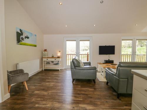 a living room with two chairs and a television at Cartmel Lodge in Cartmel