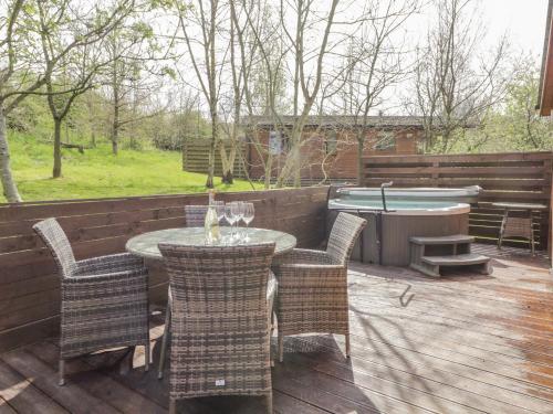 a patio with a table and chairs and a tub at Cartmel Lodge in Cartmel