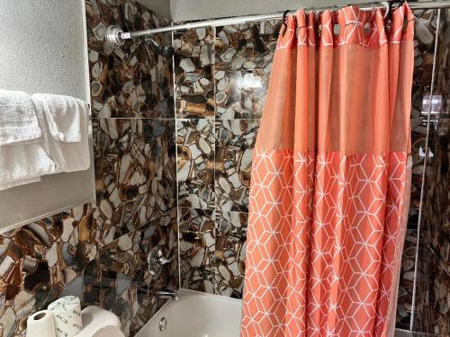 a bathroom with an orange shower curtain and a toilet at Miami Inn & Suites in Chicago