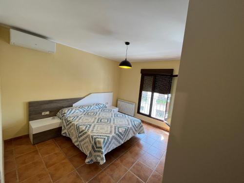 a bedroom with a bed with a comforter and a window at Alquería de Segur a in Segura de la Sierra