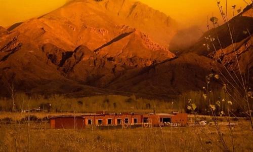 a building in a field in front of a mountain at Hotel boutique Pukarainca in Uspallata
