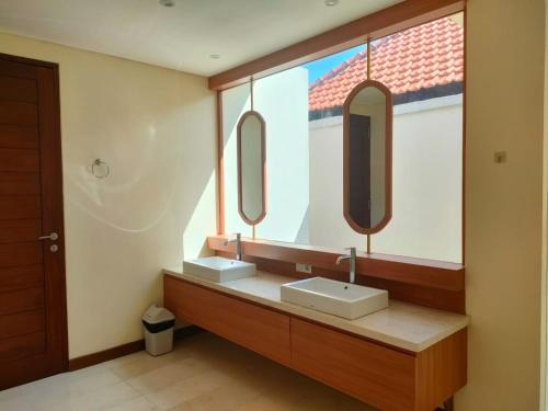 a bathroom with two sinks and two mirrors at Villa Cilinaya Ubud in Ubud