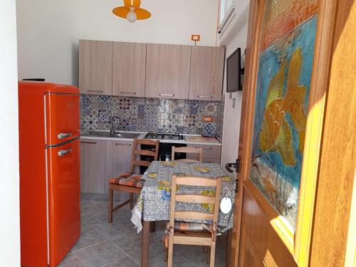 a kitchen with a table and a red refrigerator at Appartamenti Tina in Villa Restituta in Ischia