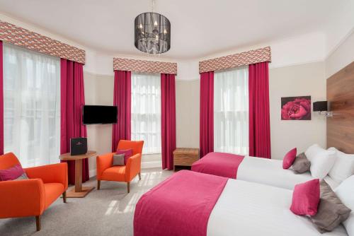 two beds in a hotel room with red curtains at New Continental Hotel; Sure Hotel Collection by Best Western in Plymouth