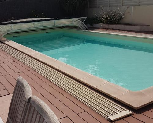une grande piscine sur une terrasse avec un banc dans l'établissement Villa bord de mer spacieuse piscine chauffé privative, à Bretignolles-sur-Mer