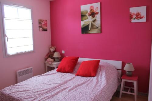 1 dormitorio con paredes rosas y 1 cama con almohadas rojas en Casa breti, en Bretignolles-sur-Mer