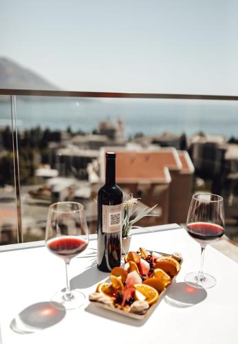 a table with two glasses of wine and a plate of food at Hotel Lusso Mare by Aycon in Budva