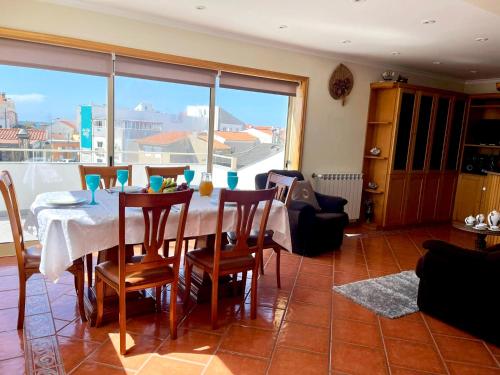 comedor con mesa y sillas y ventana grande en Xavega Apartment en Torreira