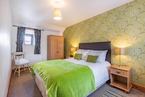 a bedroom with a bed with a green bedspread at Dairy Cottage in Llanrwst