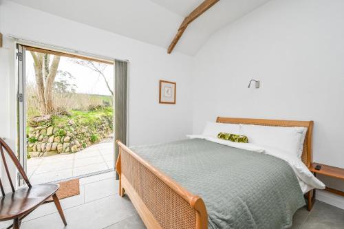 a bedroom with a bed and a balcony at Cosy Rural Barn with Private Garden & Forest - The Cart Barn in Tavistock