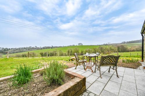 a patio with a table and chairs and a field at Cosy Rural Barn with Private Garden & Forest - The Cart Barn in Tavistock
